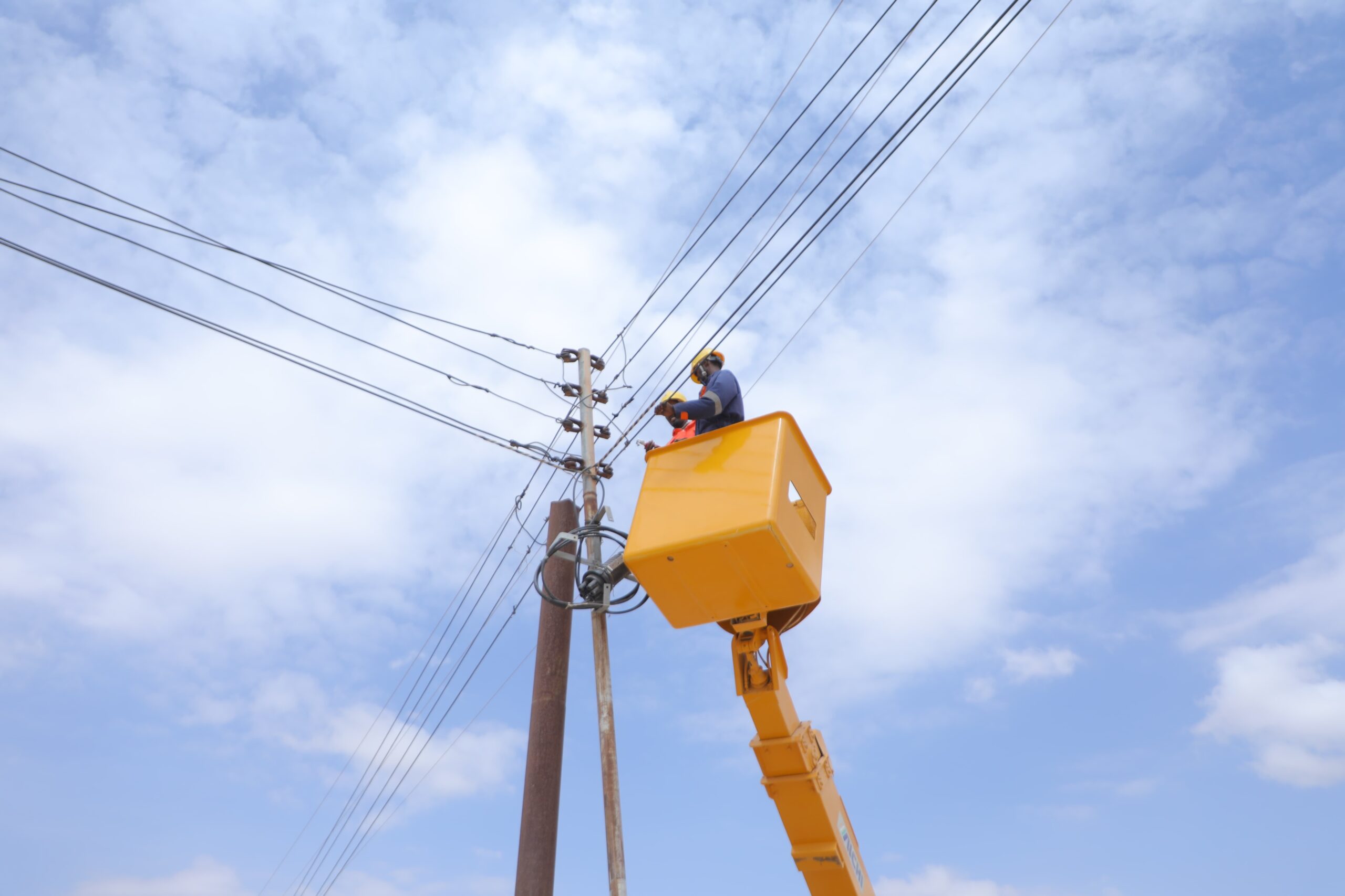 2 electricians in a boom truck fixing power lines.