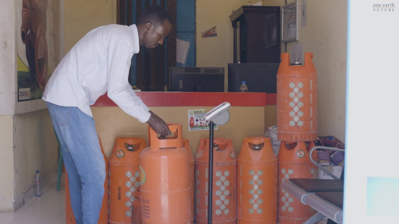 Puntland Petroleum worker weighing an orange container full of petroleum on a scale.