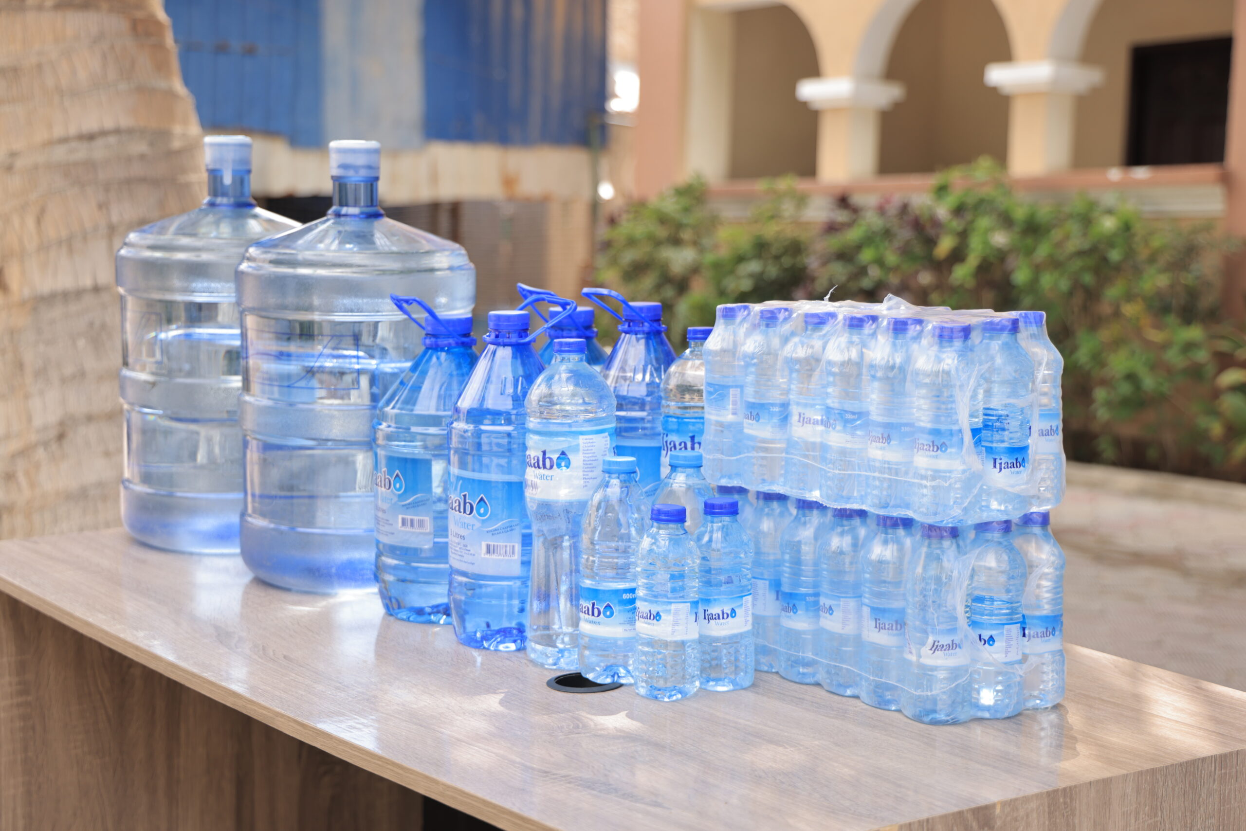 Different sized water bottoms together on a clean table outside Ijaabo factory.