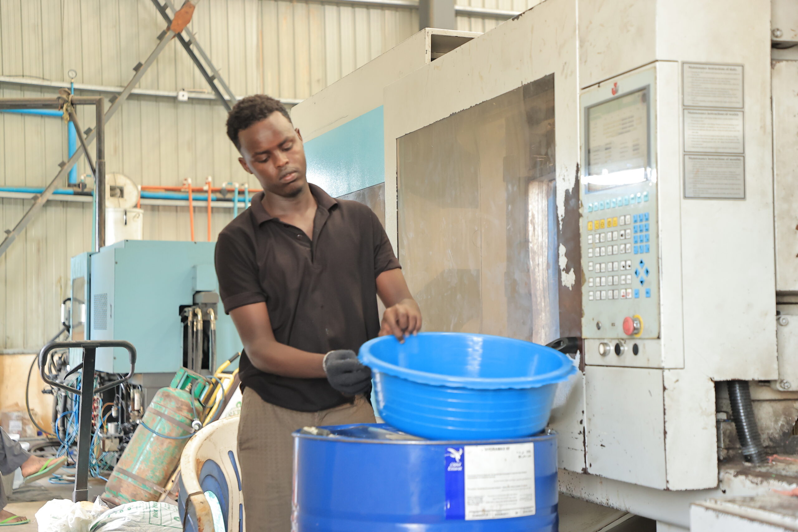 Somplastic employee inside the factory putting the finishing touches on a round, blue container