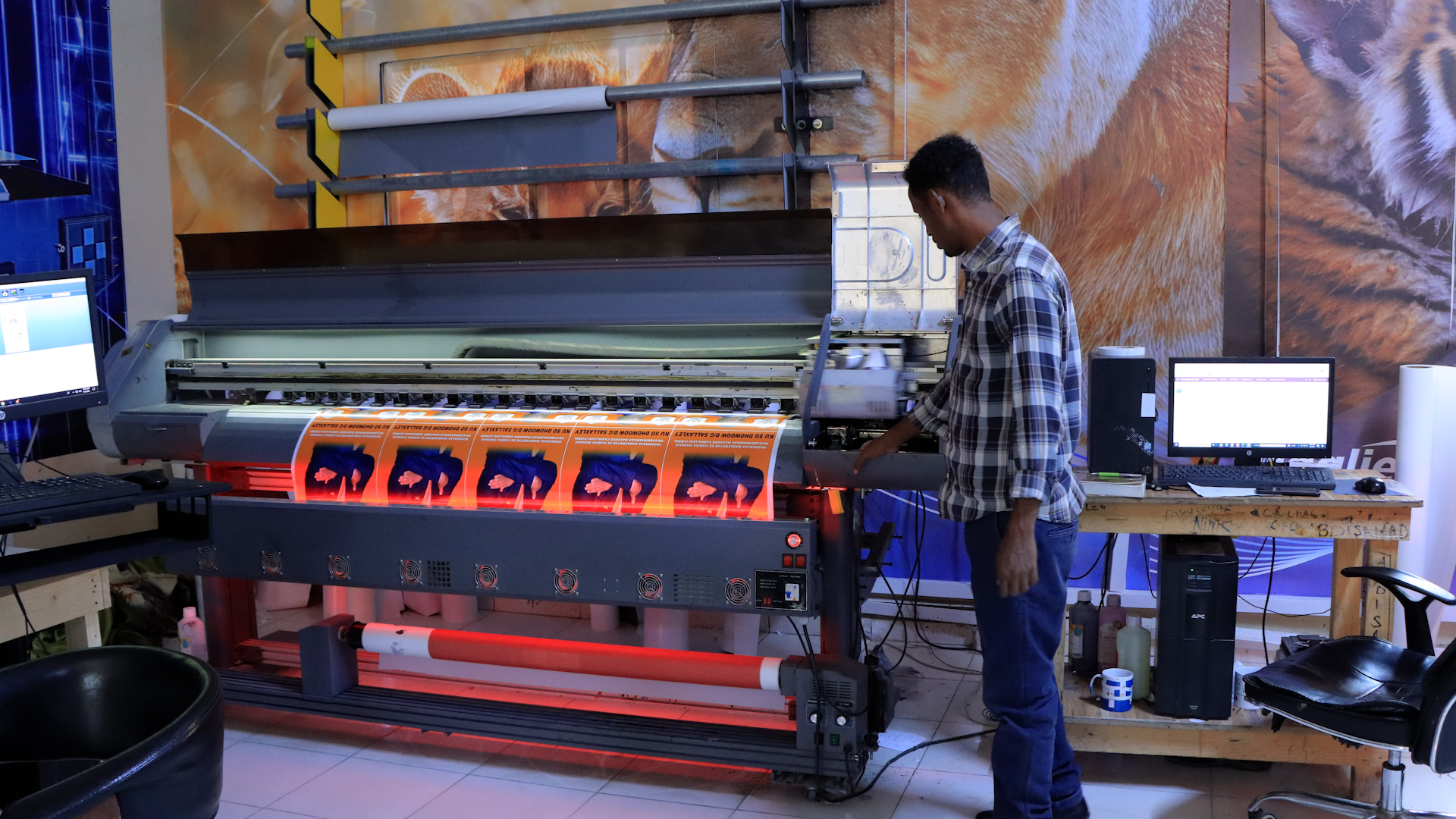 SagalJet employee standing at a large printing machine working on printing a large banner for one of their clients